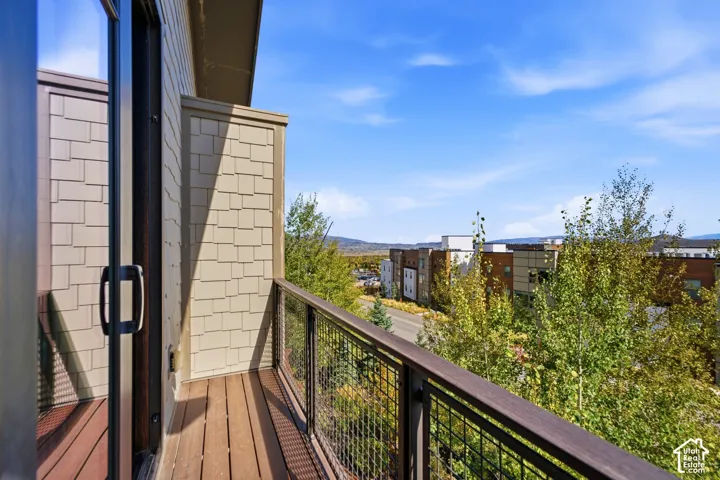 Exterior balcony featuring composite decking, wire mesh railing with a capped top rail, and shingle-style siding