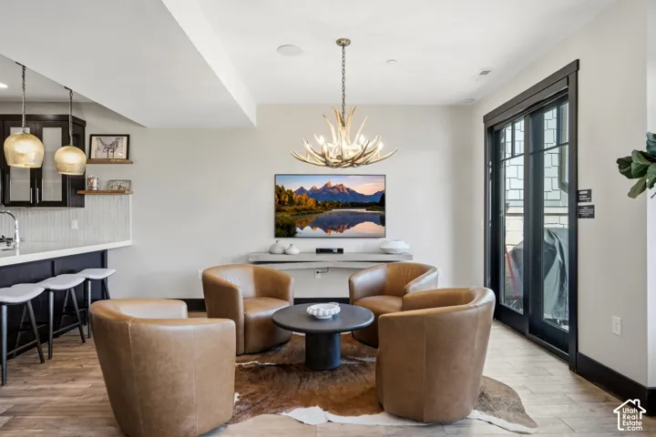 Antler chandelier, wood-finish flooring, built-in shelving, and black-framed glass patio doors