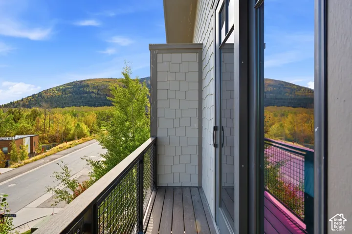 Balcony featuring composite decking, metal grid railings, cedar shake-style siding, and mountain scenery