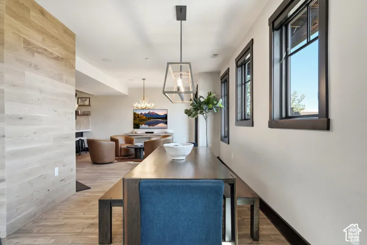 Light wood-finish paneling, geometric metal-frame pendant lighting, wood-finish flooring, and windows featuring high-contrast dark trim