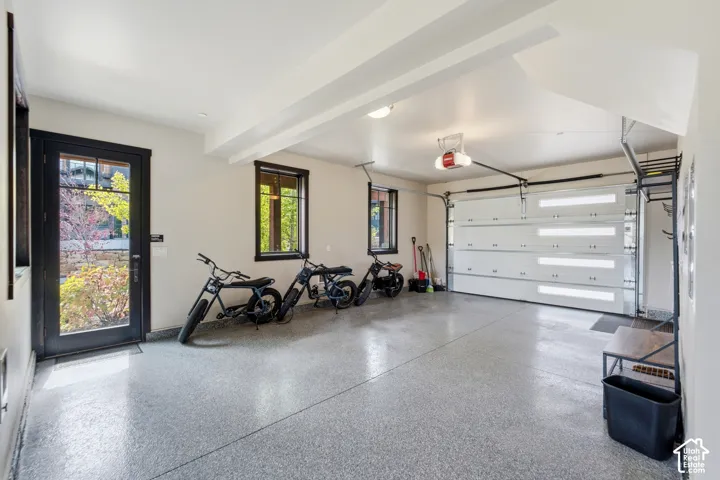 Attached garage featuring a durable epoxy-coated floor, a sectional garage door with horizontal glass panels, and a glass-paneled entry door with dark casing