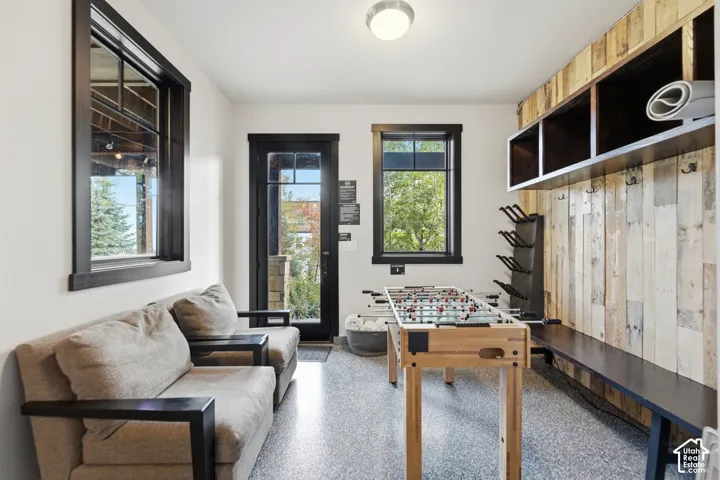Multi-purpose room featuring epoxy flooring, wood-plank wall detailing, built-in overhead storage cubbies, and dark-finished window and door trim
