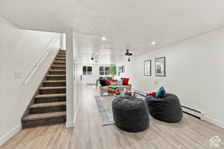 Open interior space featuring wood-finish flooring, recessed lighting, and a carpeted staircase with a white railing