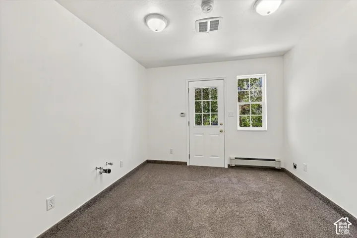 Neutral-toned wall-to-wall carpeting, white walls, flush-mount ceiling lighting, single-light exterior door with multi-pane glass, and dedicated water plumbing hookups