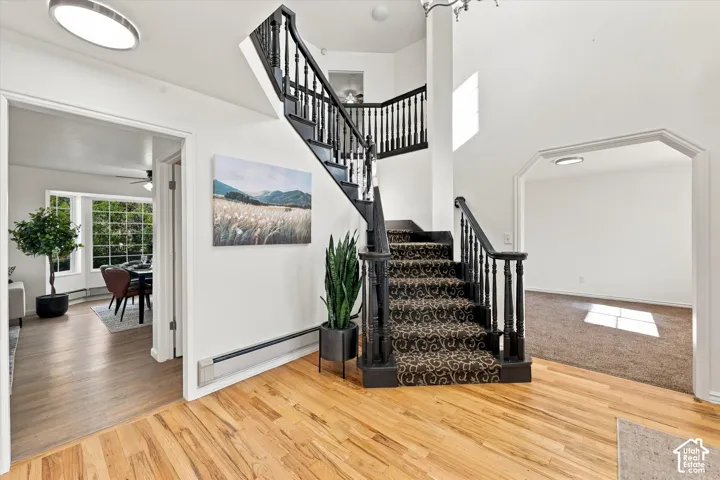 Foyer featuring wood-finish flooring, a two-story ceiling, and a staircase with a black-finish handrail and balusters