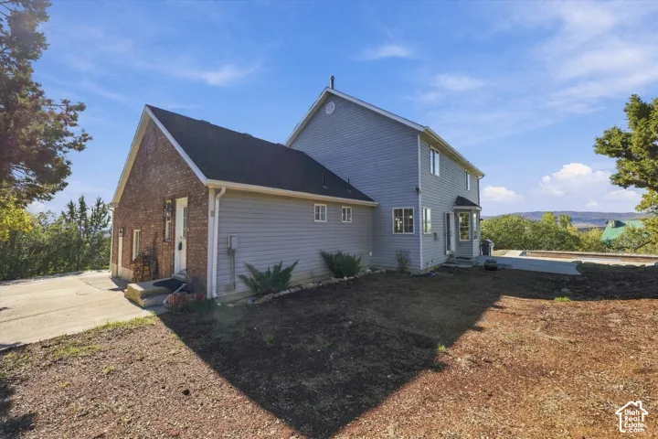 Two-story exterior featuring a brick and horizontal siding facade, a concrete driveway, and a backyard area with mature trees