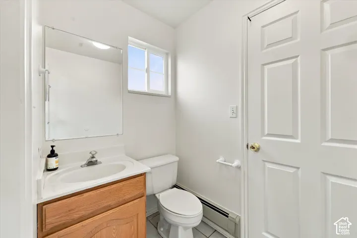 Kitchen Bathroom featuring a wood-finish vanity with an integrated sink, a large wall-mounted mirror, a two-panel interior door, and tile flooring