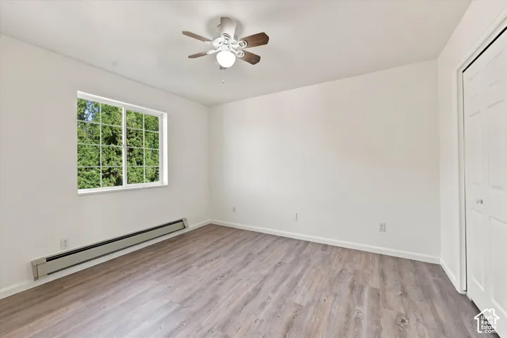 Room featuring wood-finish flooring, a multi-panel grid window, a ceiling fan with light fixture, and a bi-fold closet door