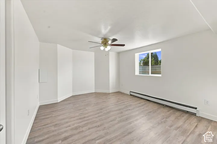Interior room featuring wood-finish flooring, a multi-pane window, and a ceiling fan with integrated lighting
