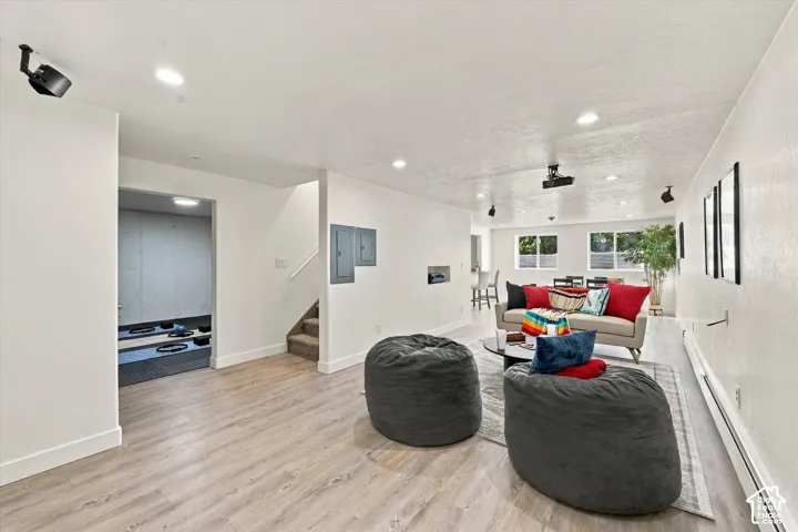 Open-concept interior featuring light wood-finish flooring, recessed lighting, adjustable directional spotlight fixtures, and dual horizontal windows