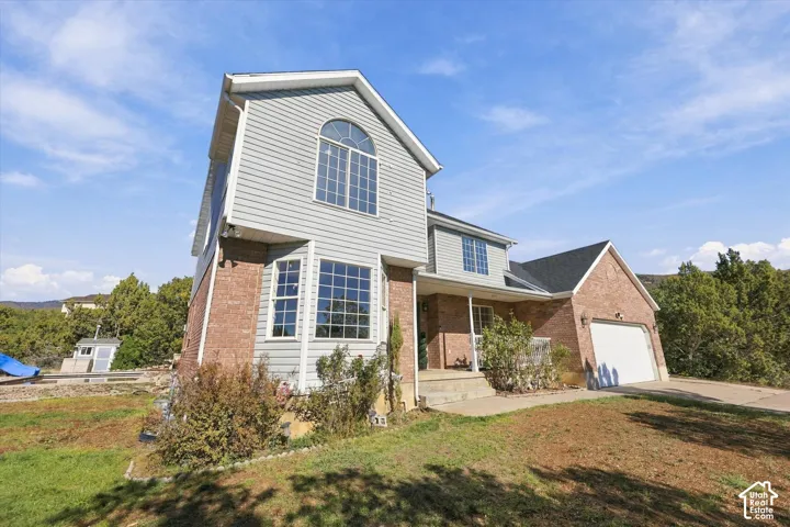 Multi-level exterior featuring a brick and horizontal siding facade, arched windows, and an attached two-car garage