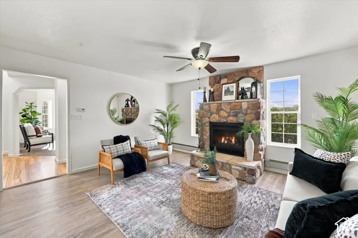 Stone-faced hearth with a firebox insert, wood-finish flooring, and a ceiling-mounted light fixture with fan blades
