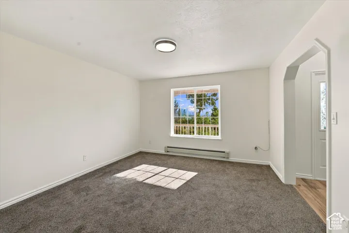 Neutral interior featuring wall-to-wall carpeting, an arched entryway, a grid-pattern window, and a flush-mount circular light fixture
