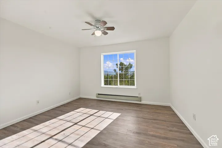 Neutral-toned interior featuring wood-finish flooring, a multi-pane window with a mountain backdrop, and a ceiling-mounted fan with integrated lighting
