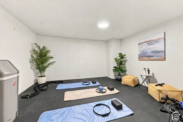 Interior room featuring poured concrete walls, textured rubber flooring, and a flush-mount ceiling light