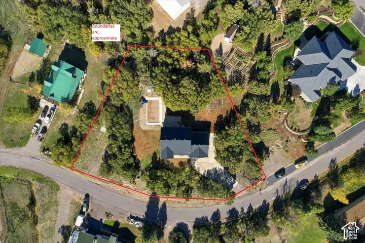 Aerial perspective of a multi-level residence featuring a paved driveway, private swimming pool, and mature trees on a sprawling lot