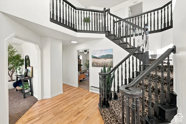 Grand foyer featuring high ceilings, wood-finish flooring, and a sweeping staircase with a black-painted wooden banister and spindles