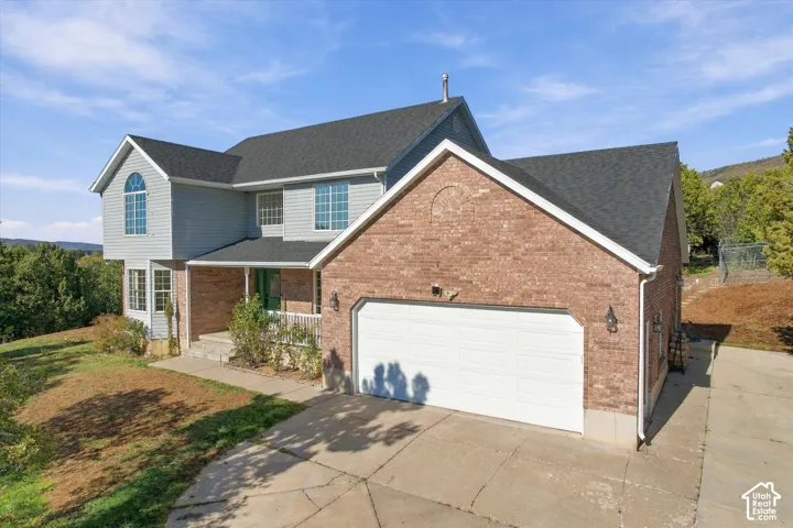Two-story exterior featuring a brick and horizontal siding facade, asphalt shingle roof, arched window detail, and a multi-car attached garage