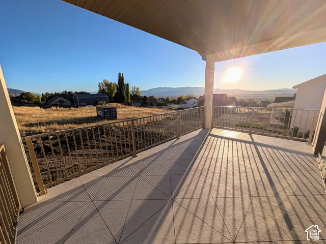 Covered balcony featuring concrete flooring with a geometric grid pattern, metal railings, and mountain scenery