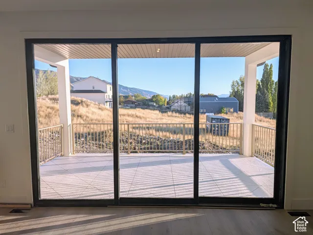 Multi-panel sliding glass doors opening to a covered patio with tile flooring, metal railings, recessed ceiling lighting, and mountain scenery