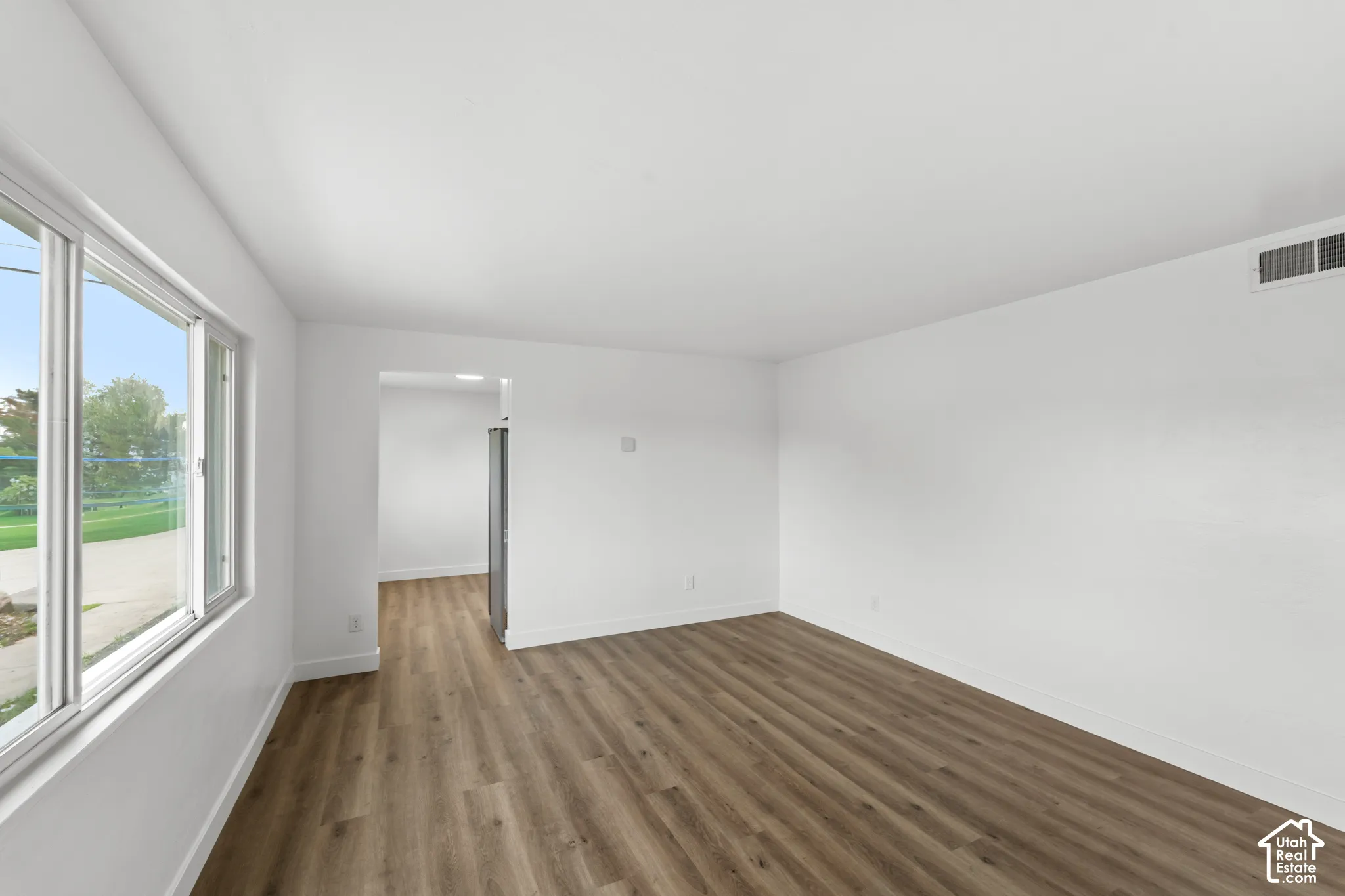Interior space featuring wood-finish flooring, white walls, and large windows providing natural light