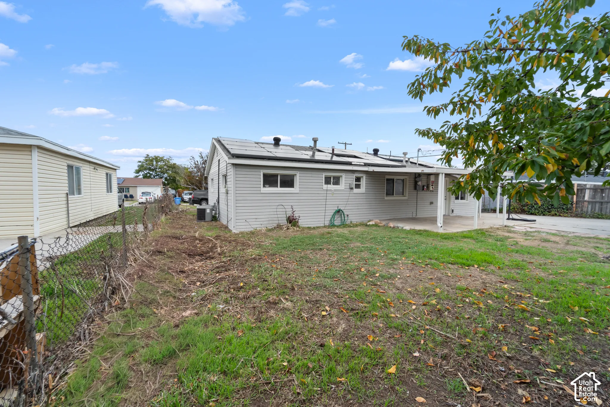 Exterior featuring grey vinyl siding, roof-mounted solar panels, and a covered concrete patio