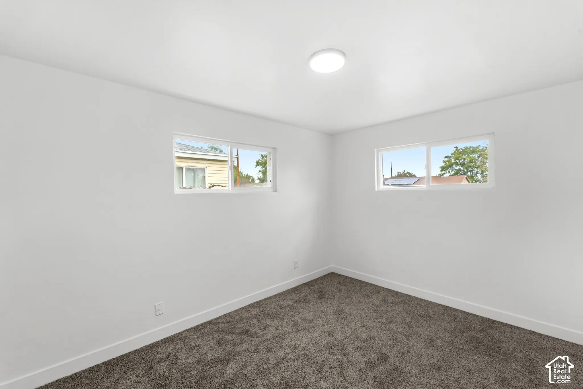 Neutral interior featuring dual sliding windows, plush wall-to-wall carpeting, and a central flush-mount ceiling light