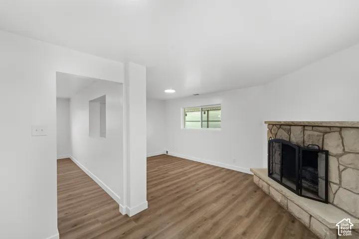 Interior space featuring wood-finish flooring, a stone-surround fireplace with a raised hearth, and a pass-through wall cutout