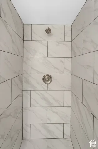 Shower enclosure featuring light-toned, large-format tile with decorative veining, offset pattern, and brushed-nickel hardware