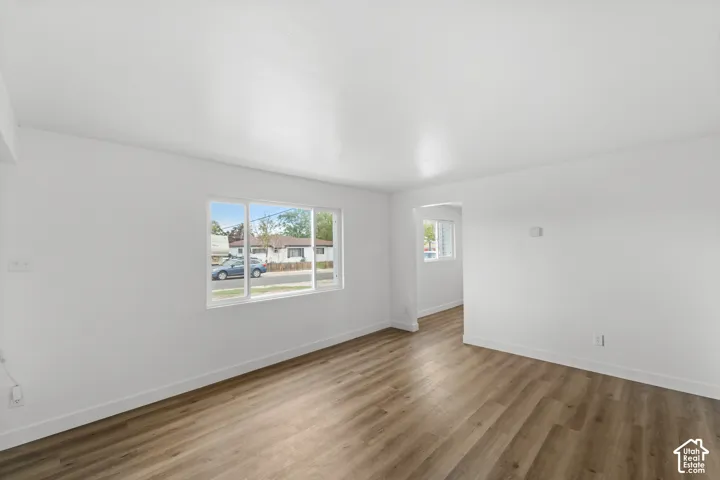 Interior space featuring wood-finish flooring, white walls, large picture windows, and an arched entry
