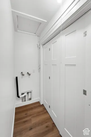 Wood-finish flooring, white shaker-style bi-fold closet doors, and recessed attic access panel