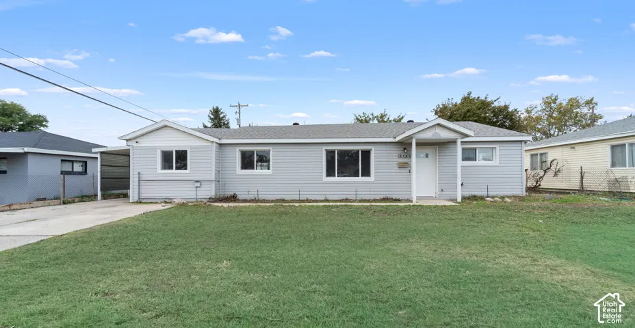 Single-story exterior featuring light-gray horizontal siding, a covered entryway, a concrete driveway, and an attached carport