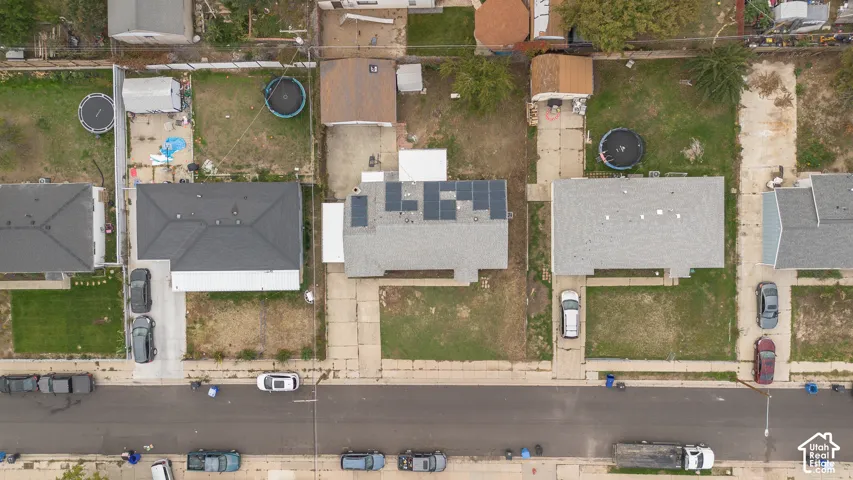 Aerial perspective of property featuring rooftop solar panels, a concrete driveway, and an expansive rear yard