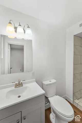 Vanity with a solid-surface countertop and integrated sink, brushed nickel faucet, three-light fixture, mirror, and shower with neutral-toned wall tile