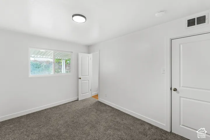 Room featuring neutral grey carpeting, bright white wall finishes, a sliding window, and two-panel interior doors