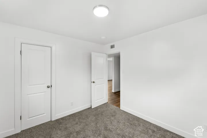 Interior space featuring neutral-toned carpeting, white walls, two-panel interior doors, and a flush-mount overhead light fixture