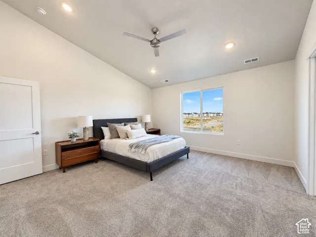 Vaulted ceiling featuring a central brushed-metal ceiling fan, recessed lighting, carpeted flooring, and a large single-pane window