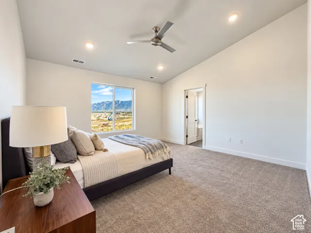 Vaulted ceiling featuring recessed lighting and a brushed-metal ceiling fan, neutral carpeting, and a large window showcasing mountain scenery