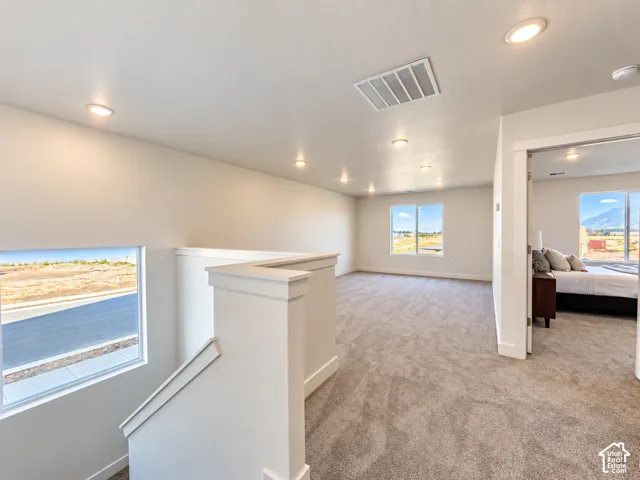 Open-concept carpeted floor plan featuring recessed lighting, large windows with mountain scenery, and a painted half-wall staircase enclosure