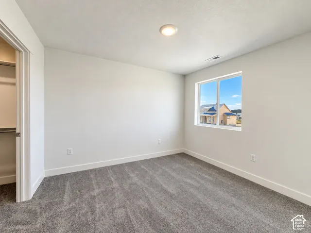 Neutral-toned wall-to-wall carpeting, recessed ceiling lighting, and a reach-in closet featuring built-in shelving