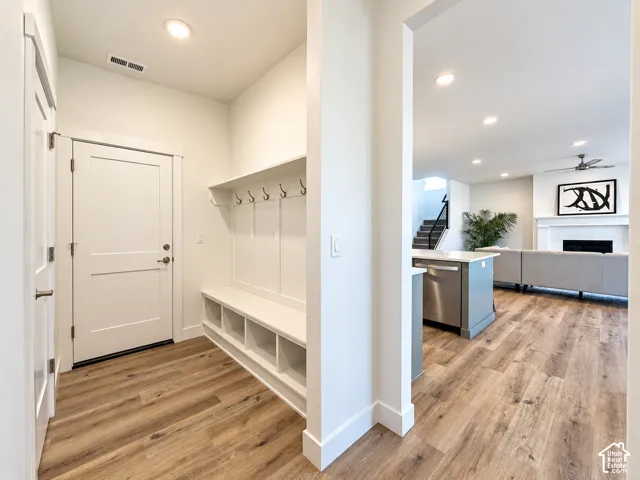 Built-in mudroom bench with integrated cubbies and coat hooks, wood-finish flooring, and recessed lighting