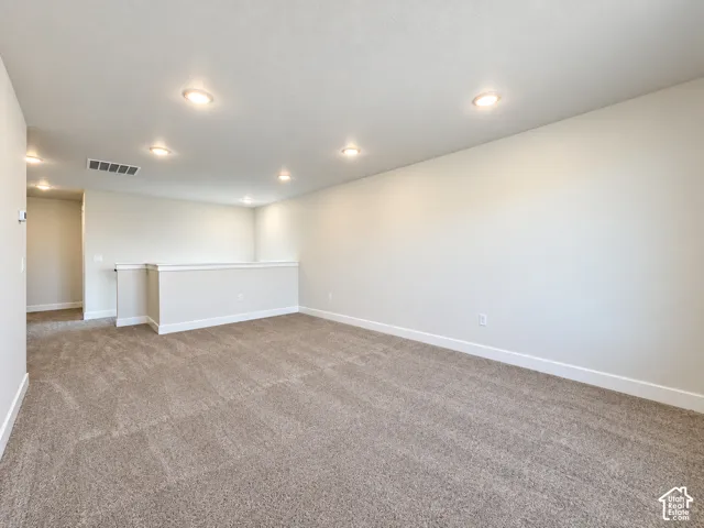 Neutral-toned wall paint, recessed lighting, and carpeting