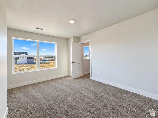 Neutral-toned interior featuring wall-to-wall carpeting, recessed ceiling lighting, and large windows with exterior surroundings