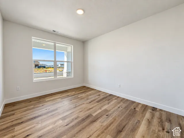 Room featuring wood-finish flooring, neutral walls, and a multi-pane window with a white frame