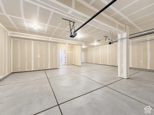 Multi-car garage featuring expansive concrete flooring, unfinished drywall, overhead door openers, and recessed lighting