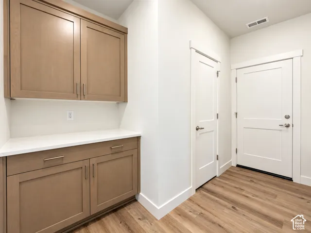 Wood-finish cabinetry featuring brushed metal hardware, solid-surface countertop, wood-finish flooring, and two-panel interior doors