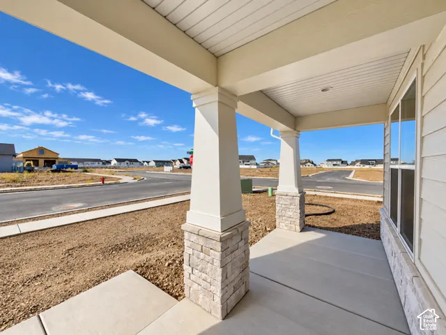 Covered porch featuring concrete flooring, tapered support columns, and stone veneer base detailing