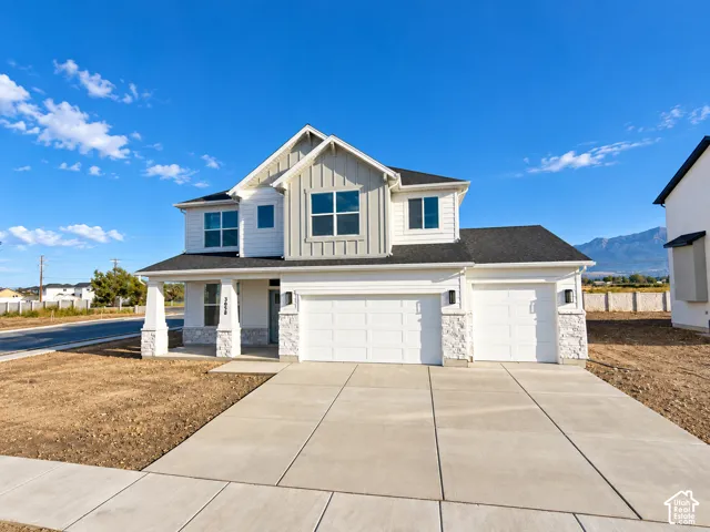 Two-story residence featuring horizontal lap siding, vertical board-and-batten gable accents, stacked stone exterior base, concrete driveway, and a three-car garage