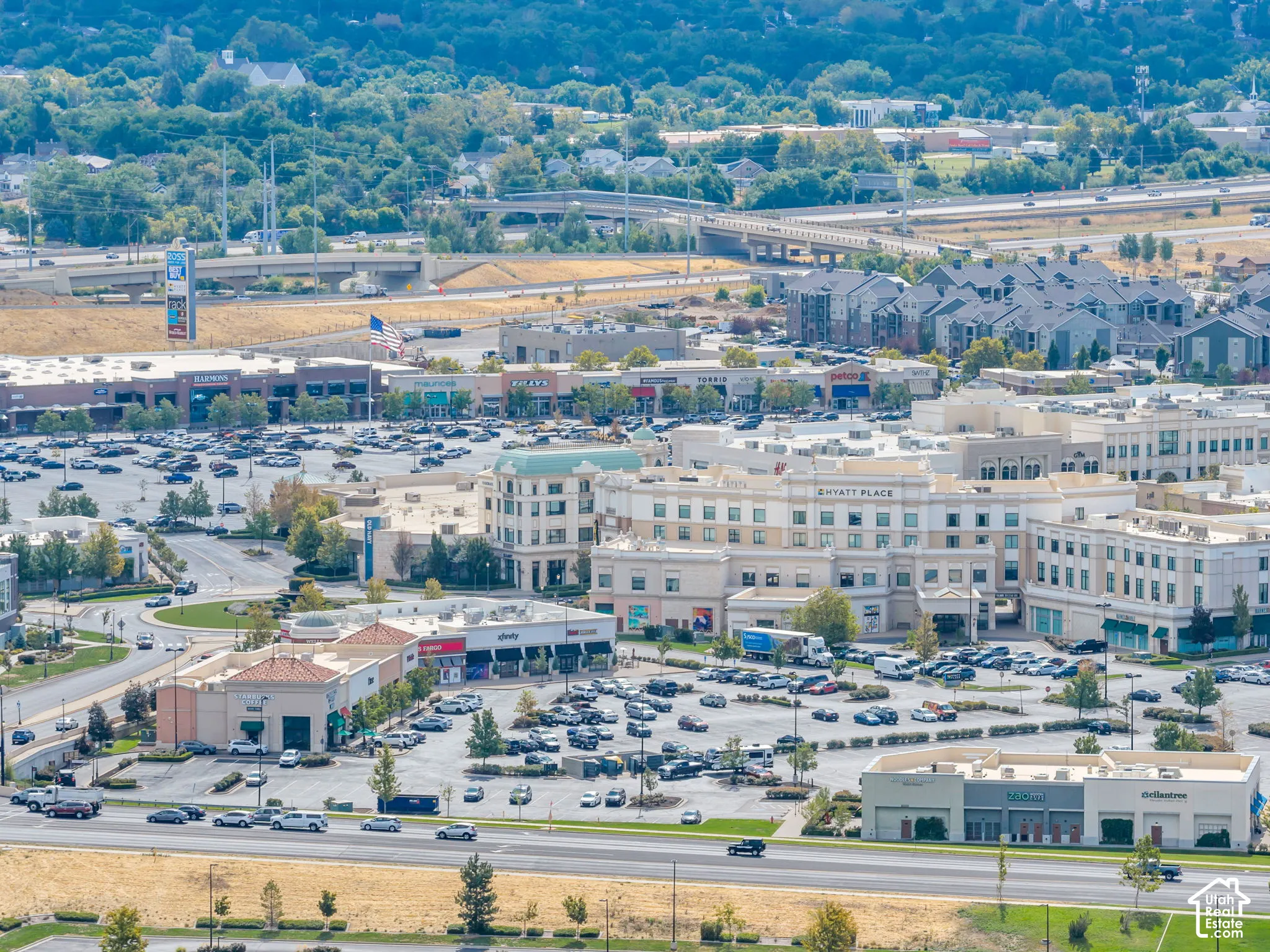 Aerial perspective of a multi-building commercial complex featuring paved surface parking, multi-story masonry structures, and prominent thoroughfare accessibility