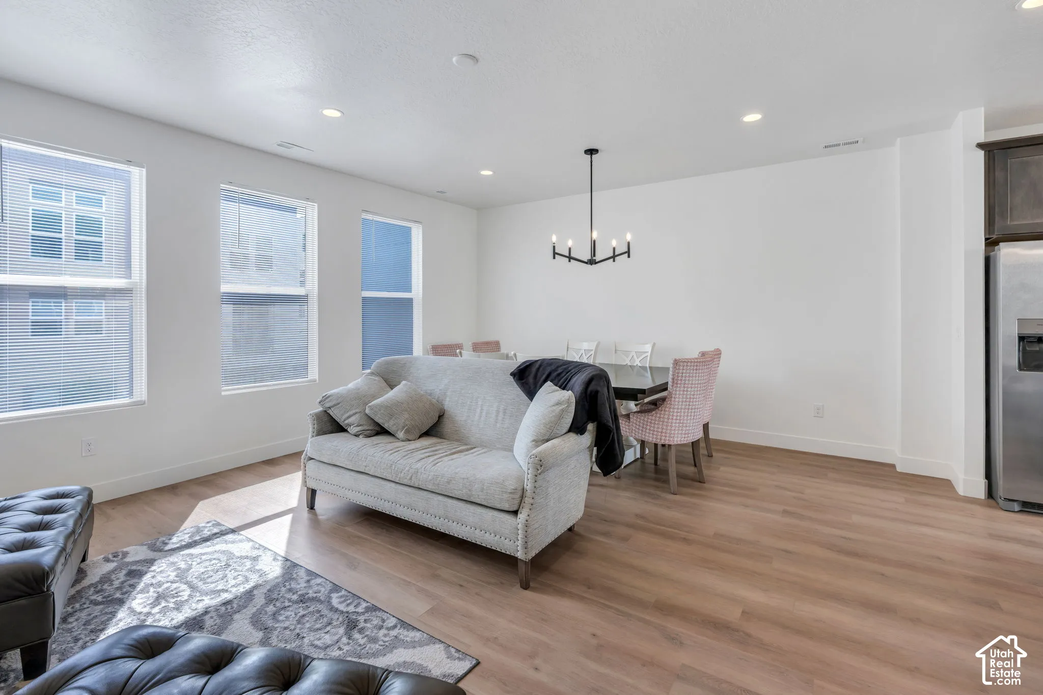 Open-concept interior featuring wood-finish flooring, recessed lighting, a modern multi-arm chandelier, and large windows